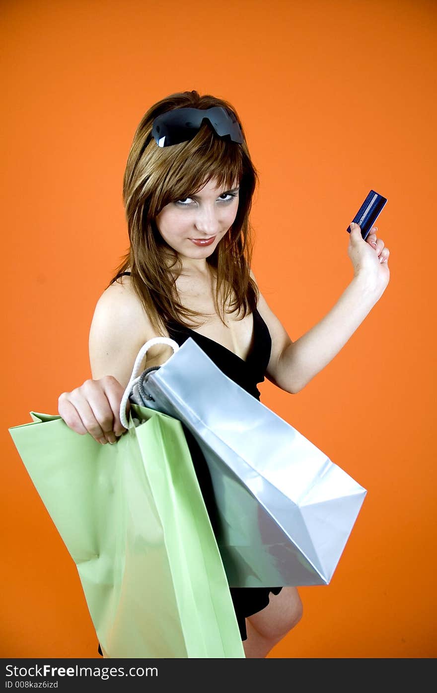 Brown haired young woman holds some shopping bags and a debit card - shopping addiction. Brown haired young woman holds some shopping bags and a debit card - shopping addiction