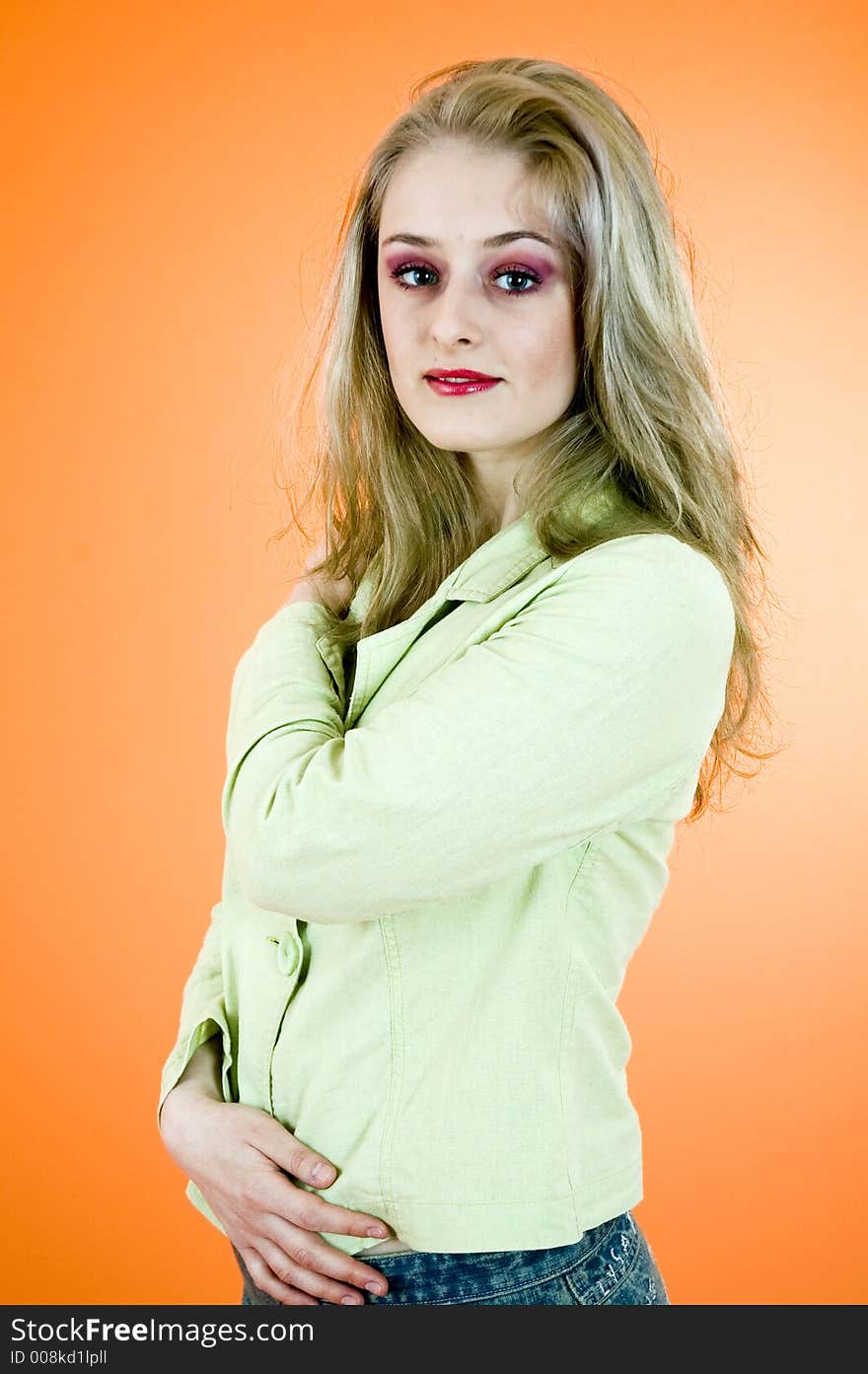 Portrait of a beautiful blond woman wearing  a casual jacket posing in a studio; nice make-up; isolated on orange background. Portrait of a beautiful blond woman wearing  a casual jacket posing in a studio; nice make-up; isolated on orange background