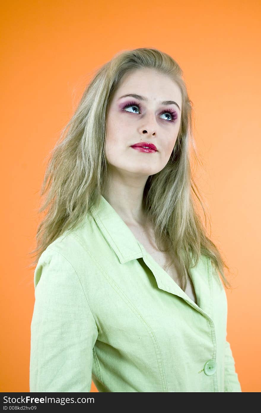 Portrait of a beautiful blond woman wearing a casual jacket posing in a studio; nice make-up; isolated on orange background. Portrait of a beautiful blond woman wearing a casual jacket posing in a studio; nice make-up; isolated on orange background