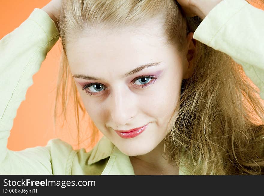 Portrait of a beautiful blond woman wearing  a casual jacket posing in a studio; nice make-up; isolated on orange background. Portrait of a beautiful blond woman wearing  a casual jacket posing in a studio; nice make-up; isolated on orange background