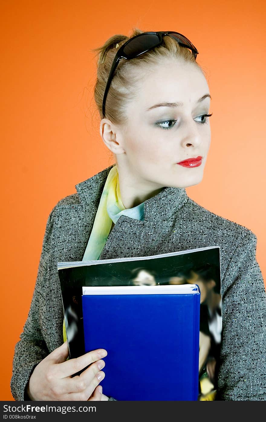 Cool looking blond student with black sunglasses, holding a book and a magazine, with a confident attitude. Cool looking blond student with black sunglasses, holding a book and a magazine, with a confident attitude