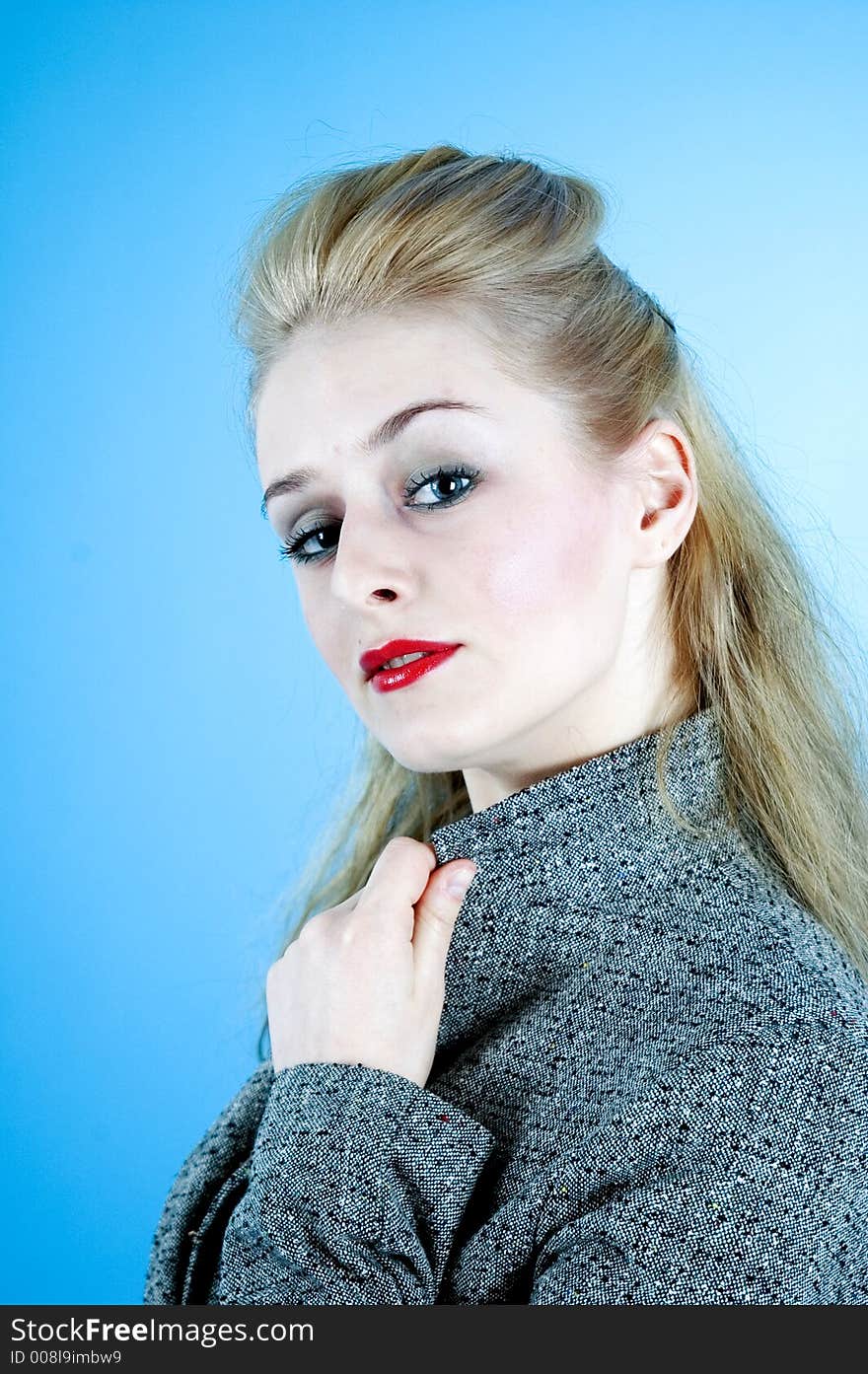 Portrait of a good-looking woman with sensual red lips and beautiful eyes; posing in a studio; isolated on blue background. Portrait of a good-looking woman with sensual red lips and beautiful eyes; posing in a studio; isolated on blue background