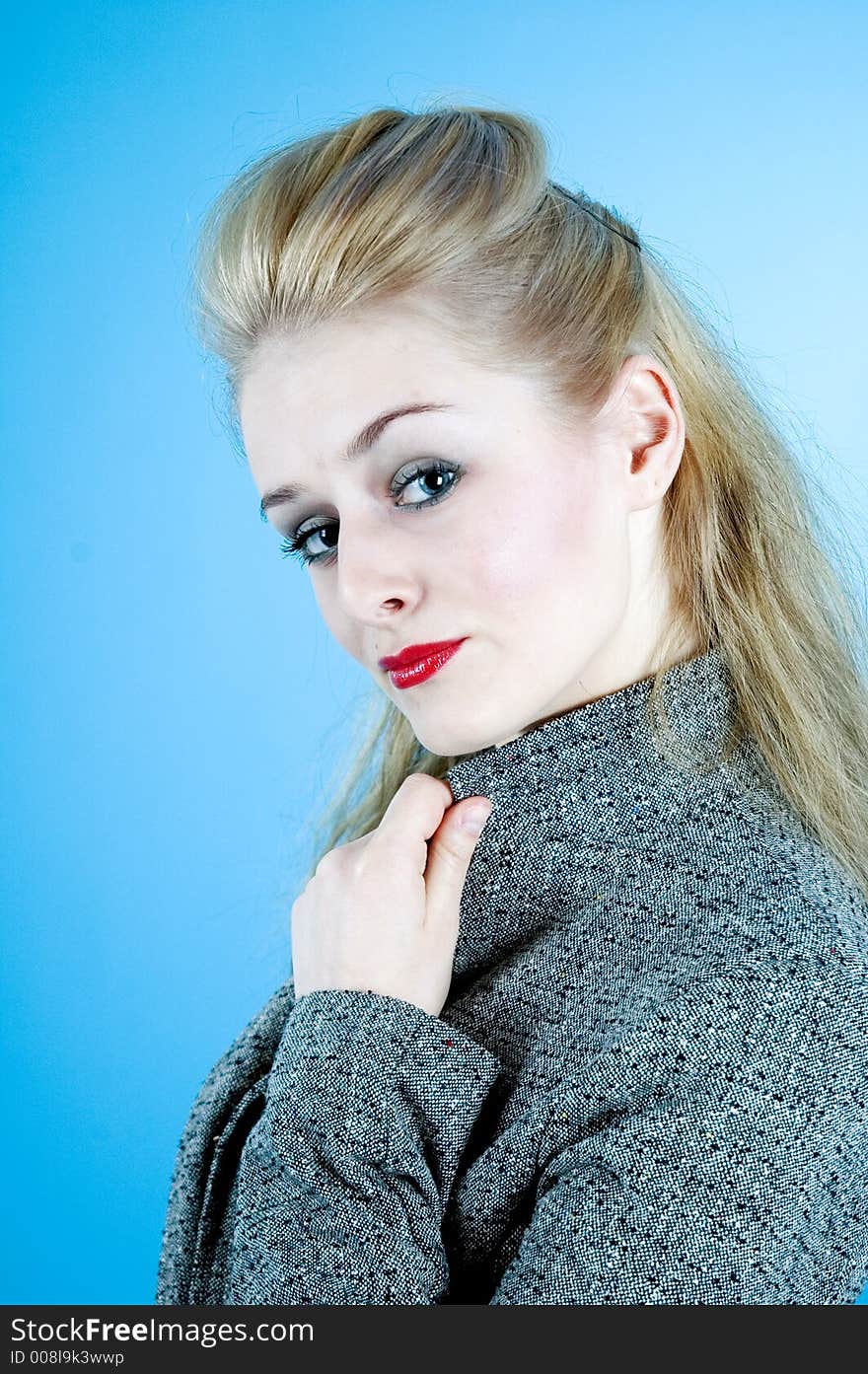 Portrait of a good-looking woman with sensual red lips and beautiful eyes; posing in a studio; isolated on blue background. Portrait of a good-looking woman with sensual red lips and beautiful eyes; posing in a studio; isolated on blue background