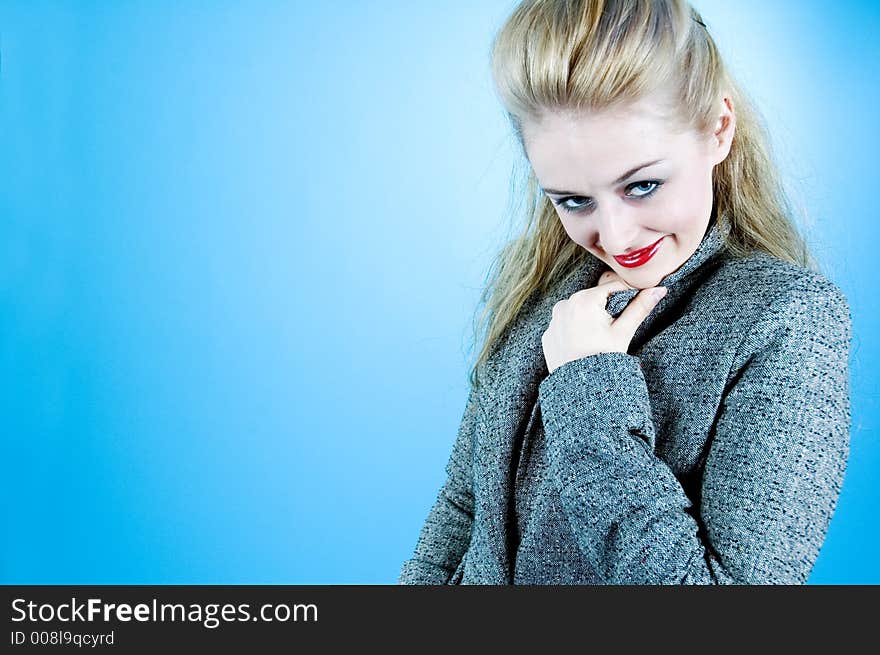 Portrait of a good-looking woman with sensual red lips and beautiful eyes; posing in a studio; isolated on blue background. Portrait of a good-looking woman with sensual red lips and beautiful eyes; posing in a studio; isolated on blue background