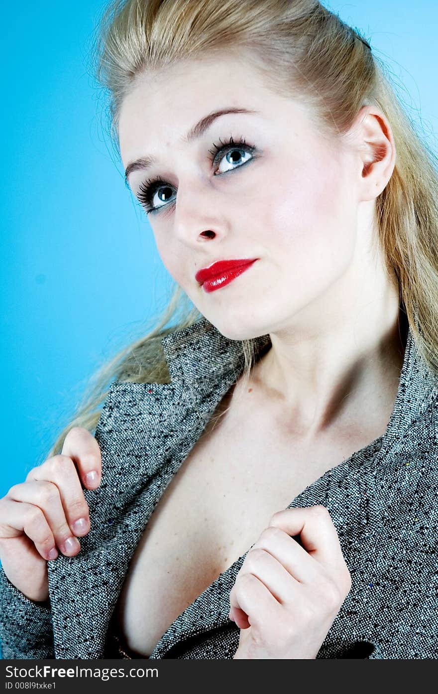 Portrait of a good-looking woman with sensual red lips and beautiful eyes; posing in a studio; isolated on blue background. Portrait of a good-looking woman with sensual red lips and beautiful eyes; posing in a studio; isolated on blue background