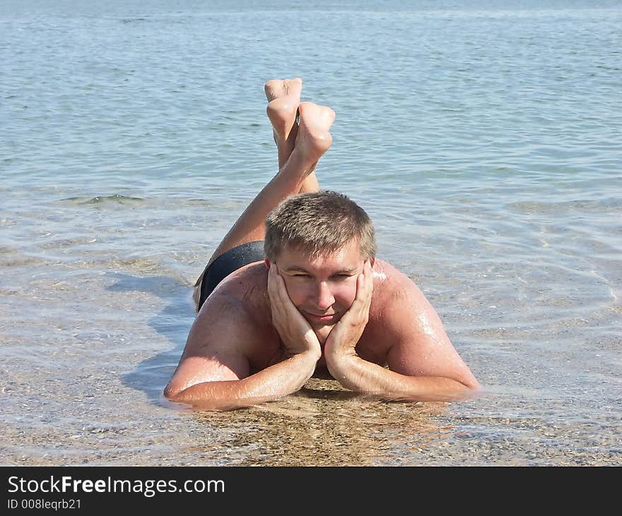 Young man posing laying in shallow sea water. Young man posing laying in shallow sea water