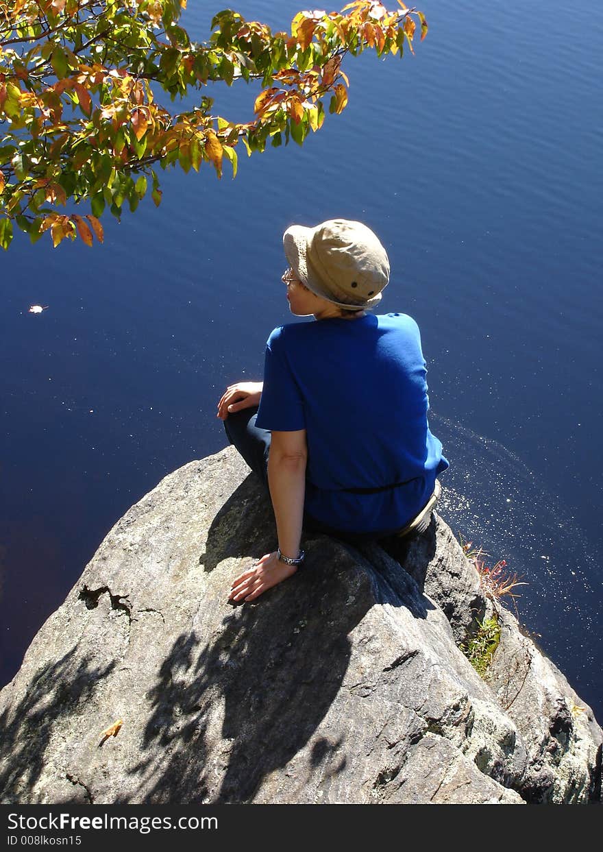 Girl  sits ashore on large stone