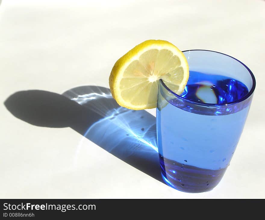 Cocktail drink decorated with lemon and served in a blue glass. Cocktail drink decorated with lemon and served in a blue glass