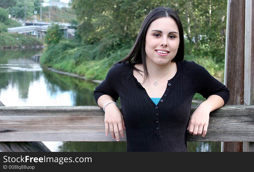 A very pretty teenage girl standing on a wooden bridge. A very pretty teenage girl standing on a wooden bridge