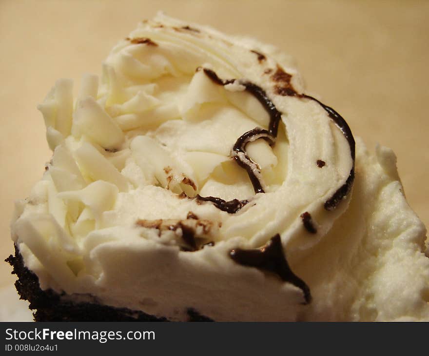 A large wedge of chocolate cake with white icing and white chocolate shavings on top. A large wedge of chocolate cake with white icing and white chocolate shavings on top.