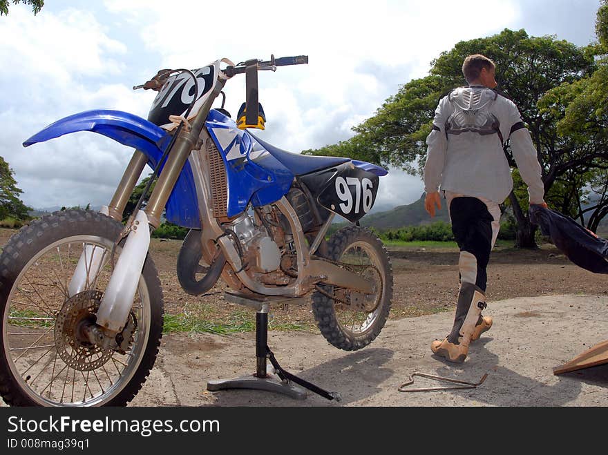 A dirt biker walking away from his bike after riding