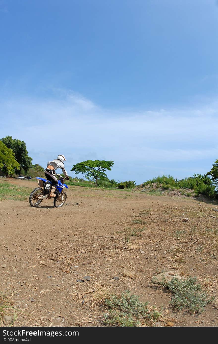 A dirt biker riding away from the camera