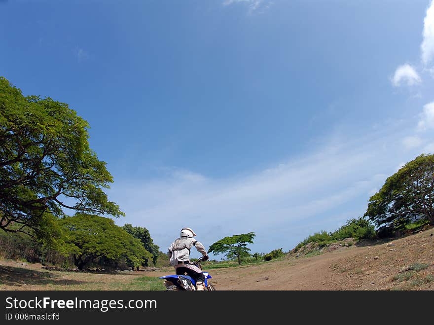 A dirt biker riding away from the camera