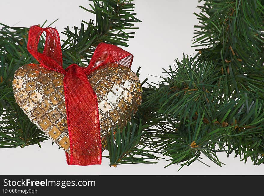 Christmas decoration gold heart with red ribbon on the pine with white background