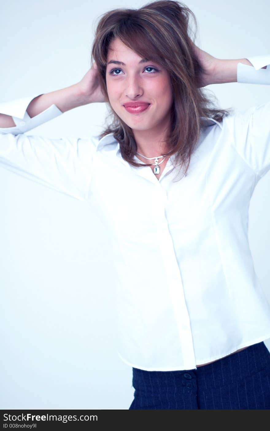 Portrait of a beautiful young girl wearing a white shirt and holding her hands on her head. Portrait of a beautiful young girl wearing a white shirt and holding her hands on her head