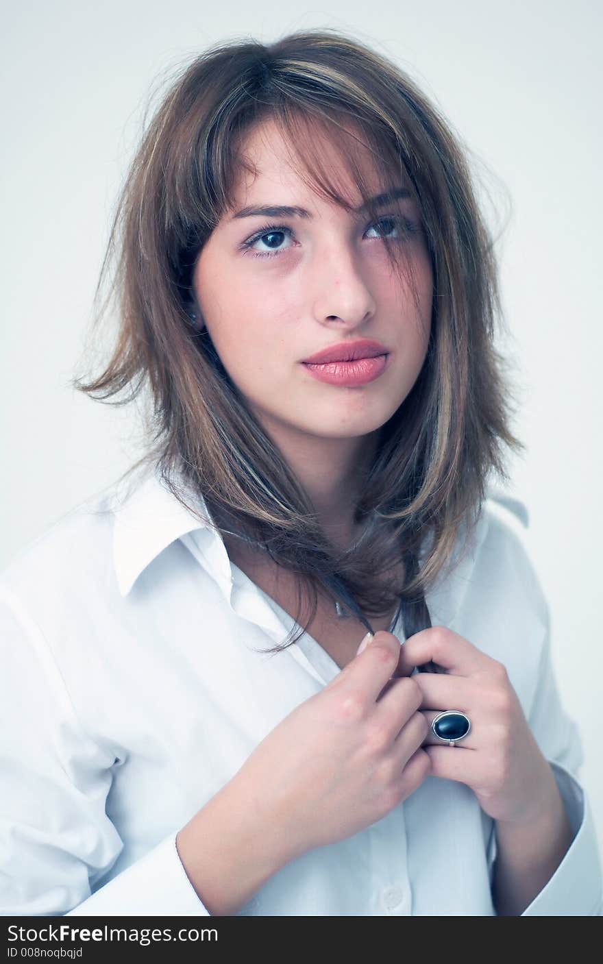 Portrait of a beautiful young girl wearing a white shirt and holding her hair with both hands. Portrait of a beautiful young girl wearing a white shirt and holding her hair with both hands