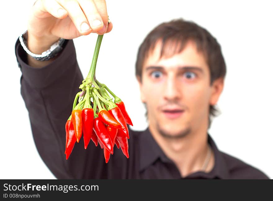 Young boy with black shirt holding a buch of red chilli peppers and having a funny expression; white background. Young boy with black shirt holding a buch of red chilli peppers and having a funny expression; white background