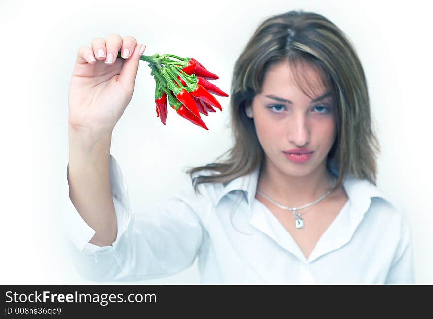 Portrait of a beautiful young girl holding a bunch of red chilli peppers in her mouth; white background. Portrait of a beautiful young girl holding a bunch of red chilli peppers in her mouth; white background