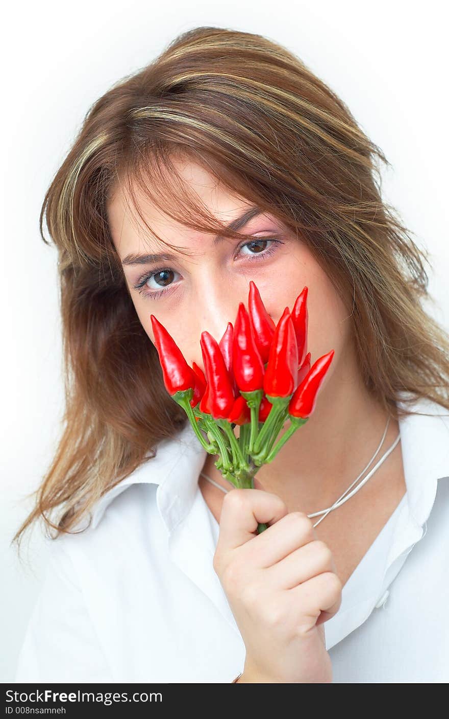 Portrait of a beautiful young girl holding a bunch of red chilli peppers in her mouth; white background. Portrait of a beautiful young girl holding a bunch of red chilli peppers in her mouth; white background