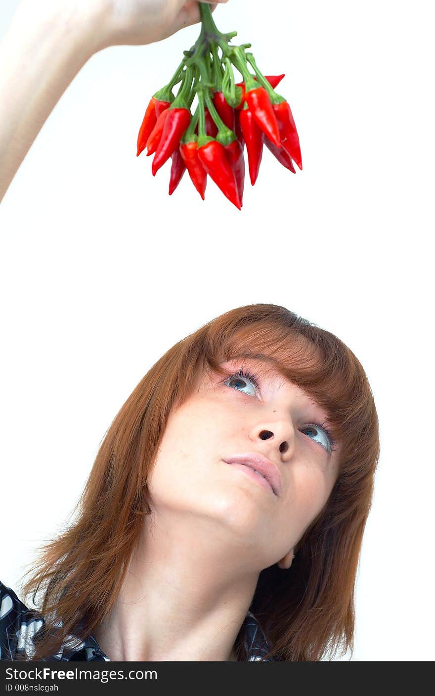 Portrait of a beautiful young girl holding a bunch of red chilli peppers over her head and looking at them; white background. Portrait of a beautiful young girl holding a bunch of red chilli peppers over her head and looking at them; white background