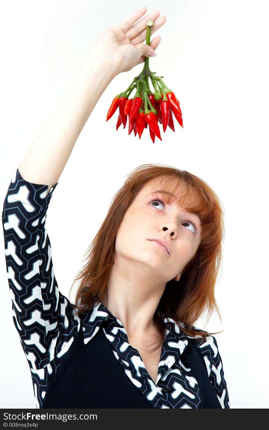 Portrait of a beautiful young girl holding a bunch of red chilli peppers over her head and looking at them; white background. Portrait of a beautiful young girl holding a bunch of red chilli peppers over her head and looking at them; white background