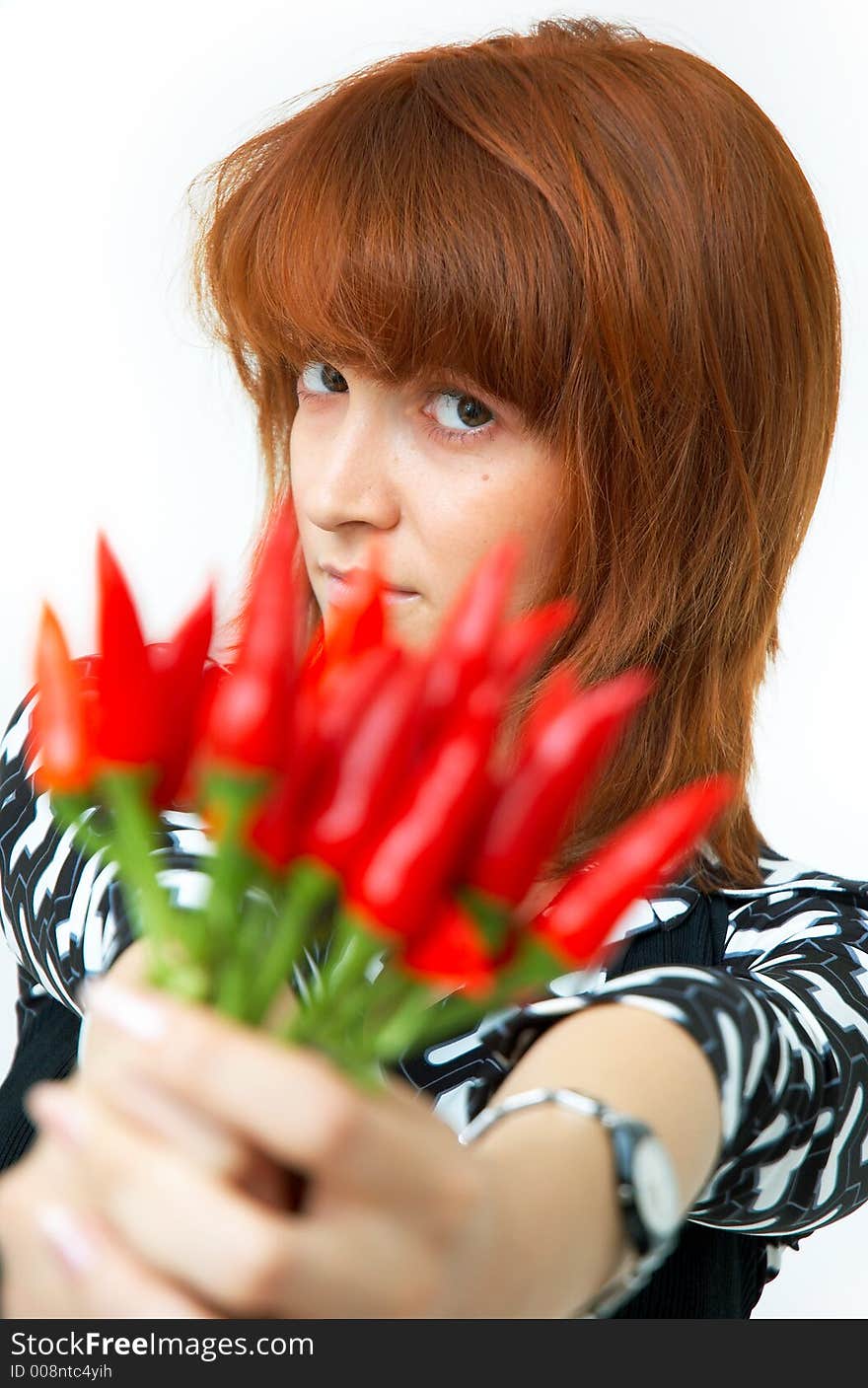 Portrait of a beautiful young girl holding a bunch of red chilli peppers over her head and looking at them; white background. Portrait of a beautiful young girl holding a bunch of red chilli peppers over her head and looking at them; white background