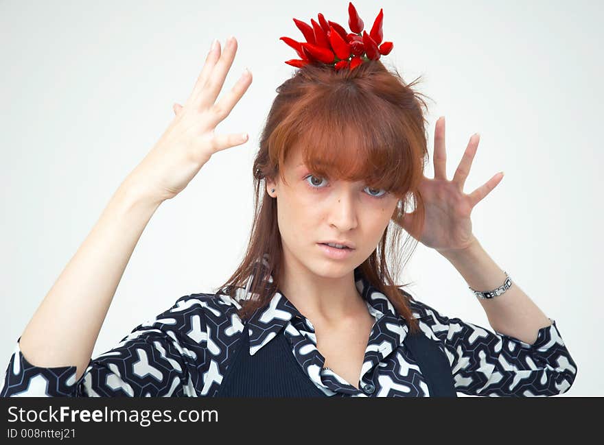 Portrait of a beautiful young girl holding a bunch of red chilli peppers over her head and looking at them; white background. Portrait of a beautiful young girl holding a bunch of red chilli peppers over her head and looking at them; white background