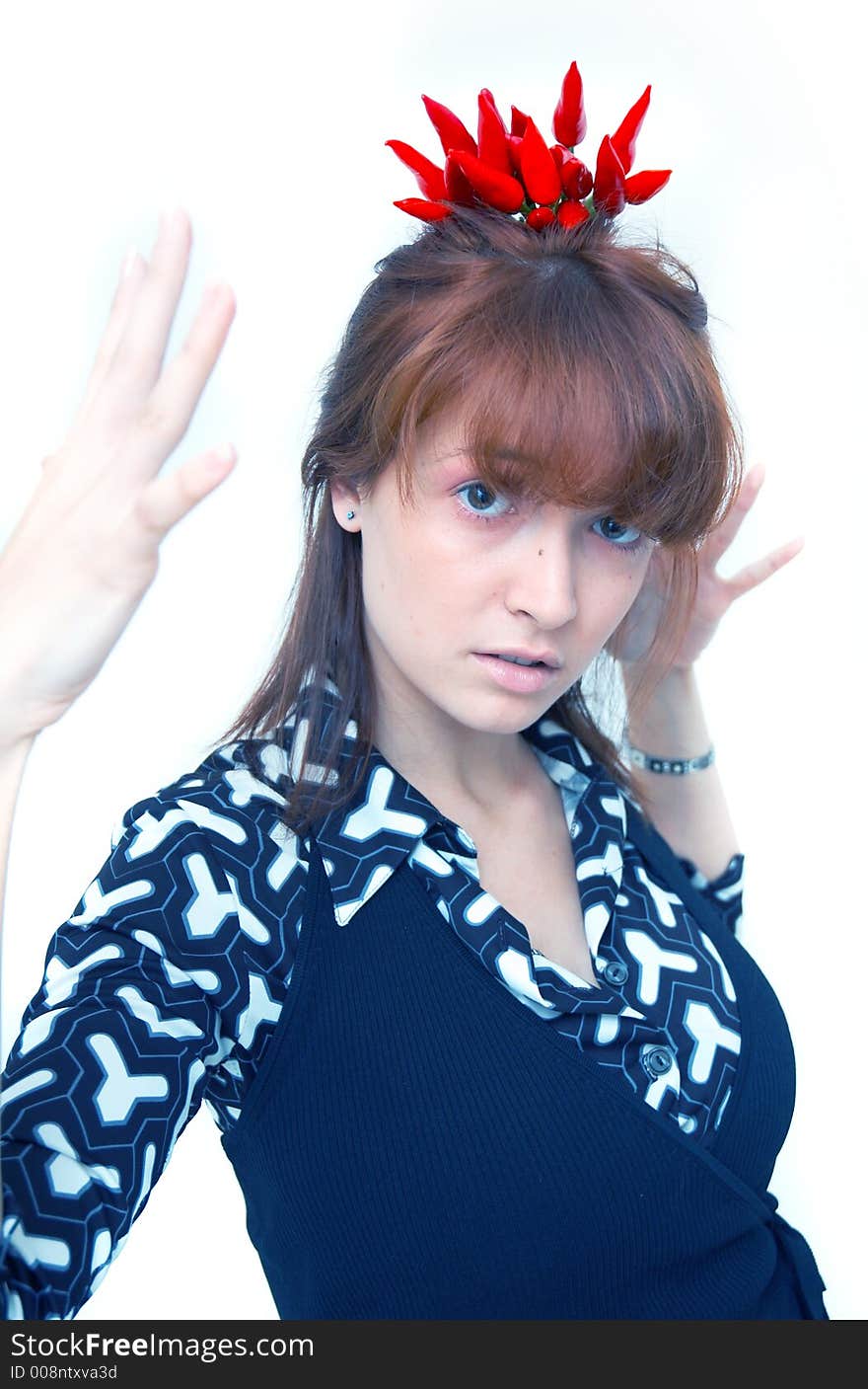 Portrait of a beautiful young girl holding a bunch of red chilli peppers over her head and looking at them; white background. Portrait of a beautiful young girl holding a bunch of red chilli peppers over her head and looking at them; white background