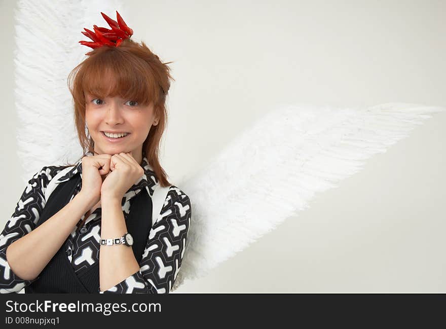 Portrait of a beautiful girl with angel wings and a bunch of red chilli peppers as a acessory for the hair. Portrait of a beautiful girl with angel wings and a bunch of red chilli peppers as a acessory for the hair