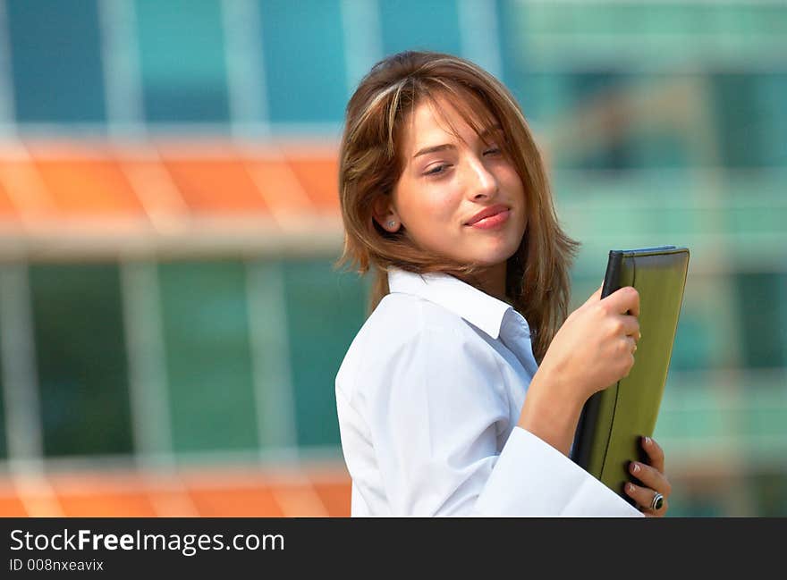 Portrait of a beautiful young girl with casual clothes holding an agenda in her hands in front of a office buiding. Portrait of a beautiful young girl with casual clothes holding an agenda in her hands in front of a office buiding