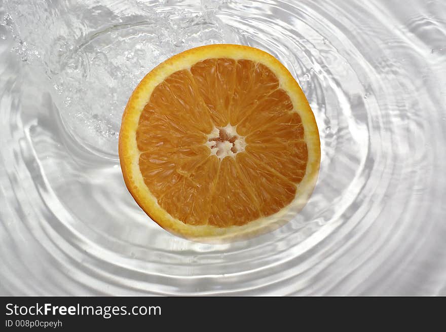 Slice of orange splashing into water