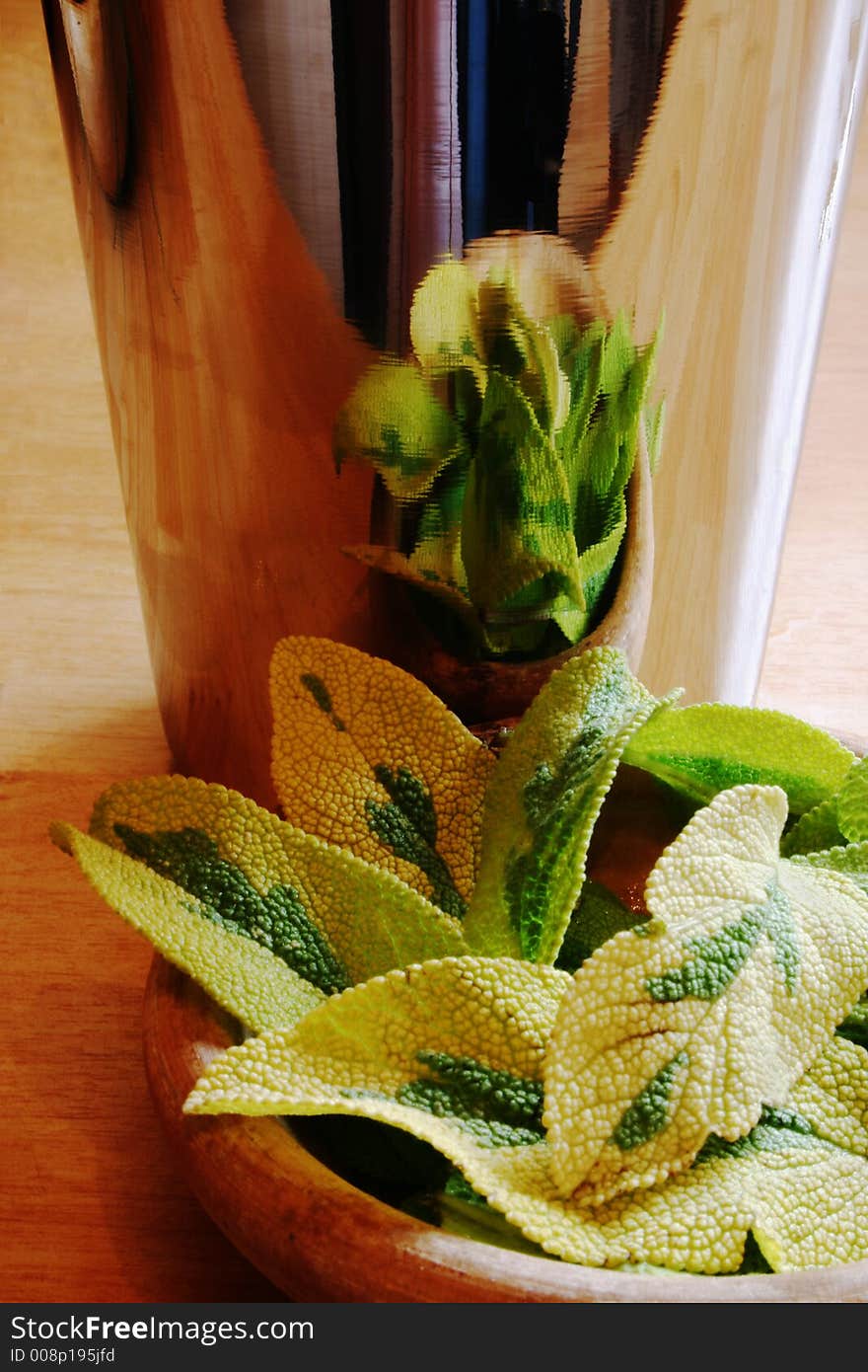 Sage leaves in a wooden bowl reflected in metal mug. Sage leaves in a wooden bowl reflected in metal mug