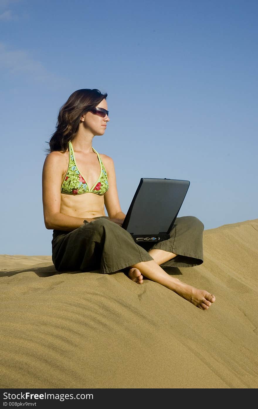 Girl working on her laptop in the dunes in Gran Canaria. Girl working on her laptop in the dunes in Gran Canaria