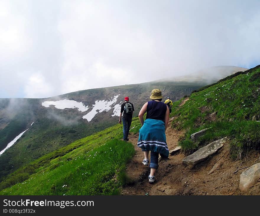 People going up to the peak covered by clouds. People going up to the peak covered by clouds