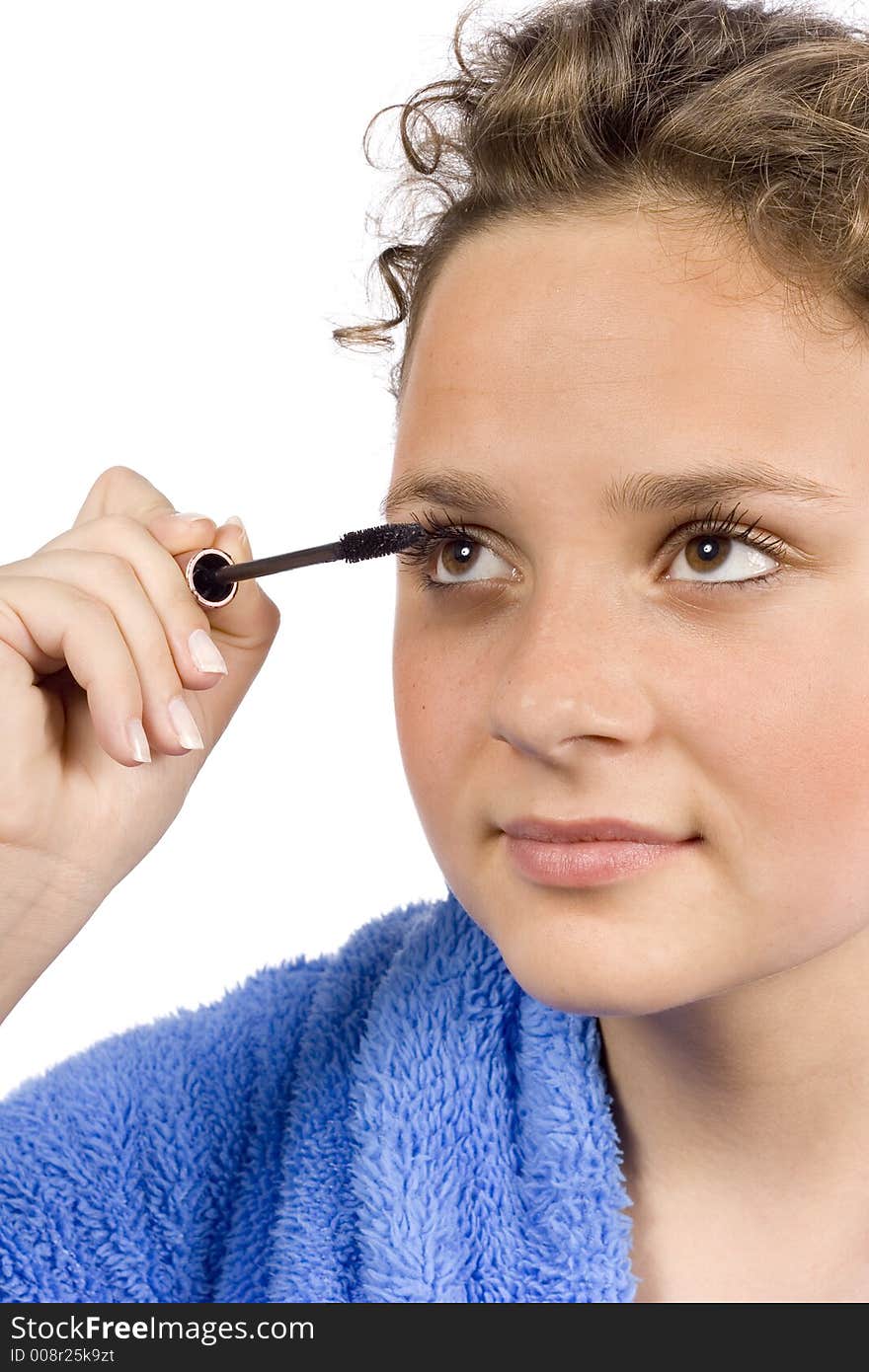 Isolated on white young woman dressed blue bathrobe putting mascara