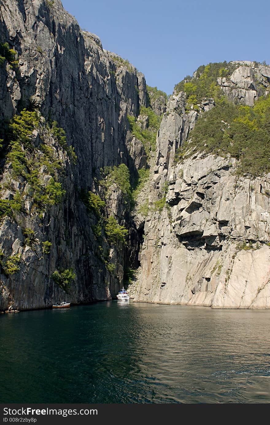 Picture of boats in fjord near rocky coast.