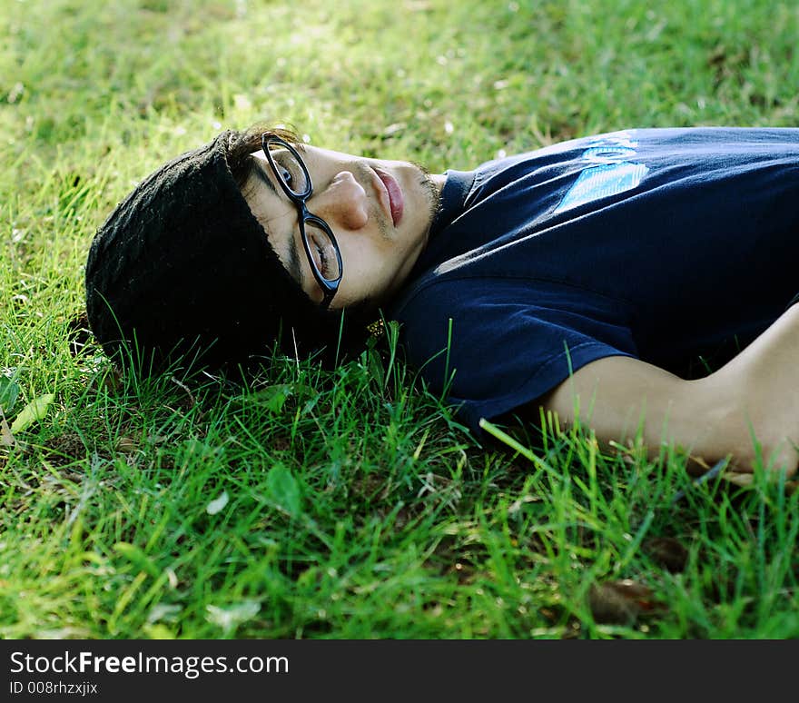 A person with glasses laying in the grass. A person with glasses laying in the grass