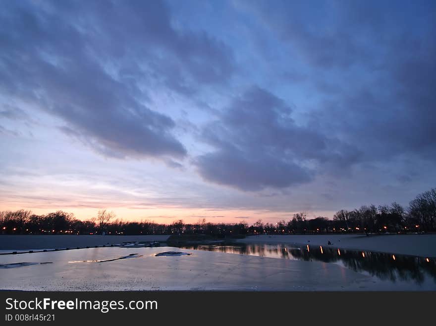 Lake under ice with magnificent cloudy sky at sunset