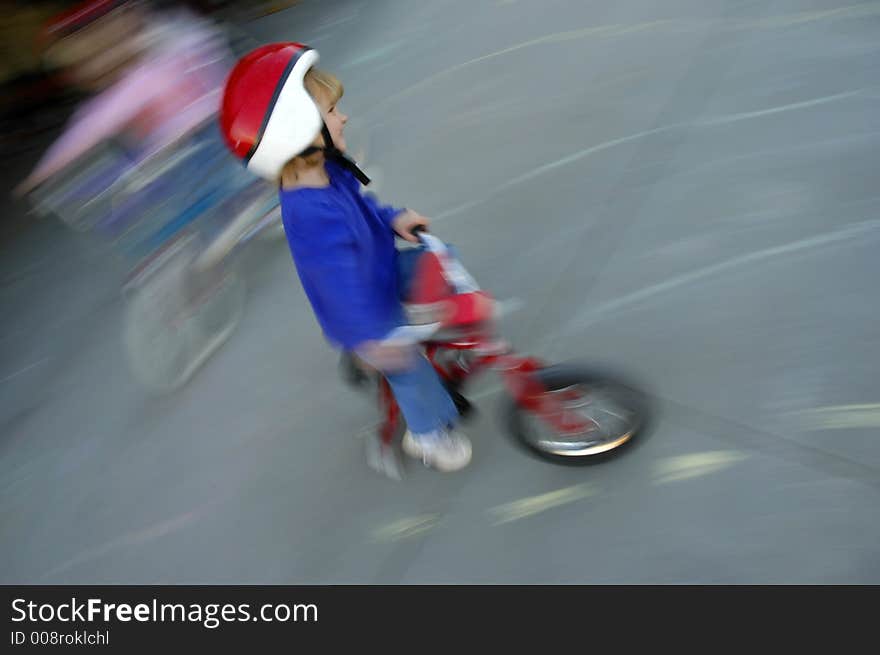 Motion shot of little girl biking with red helmet