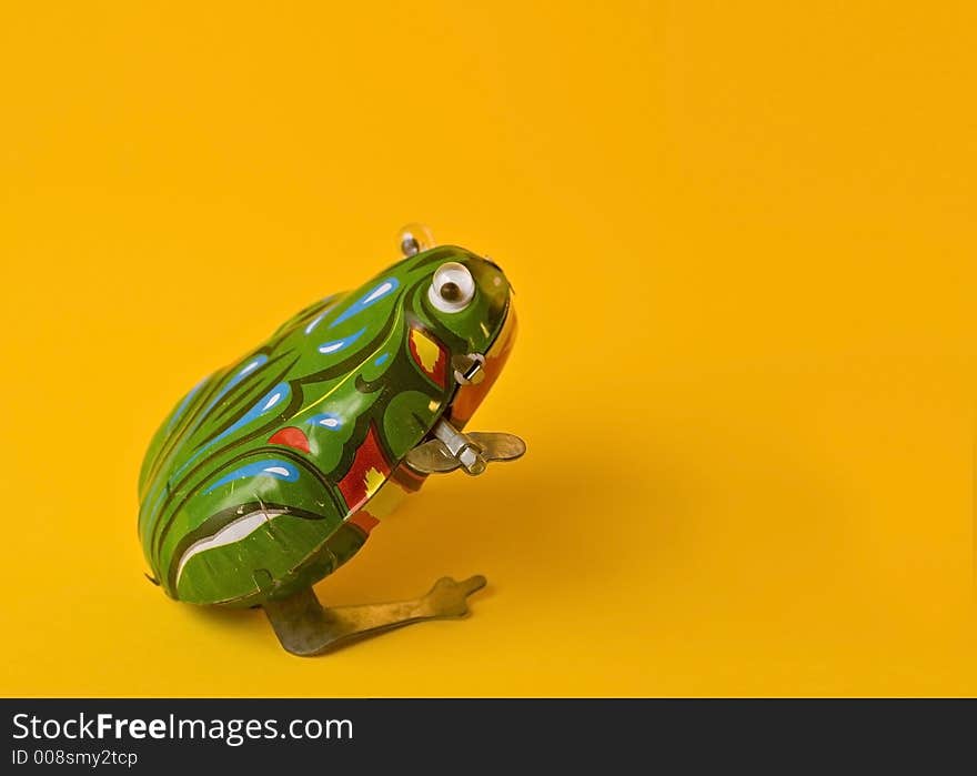 Mechanical TOY frog on yellow. Mechanical TOY frog on yellow