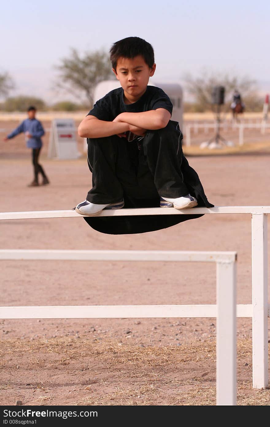 Boy kneeling on rail with arms crossed. Boy kneeling on rail with arms crossed