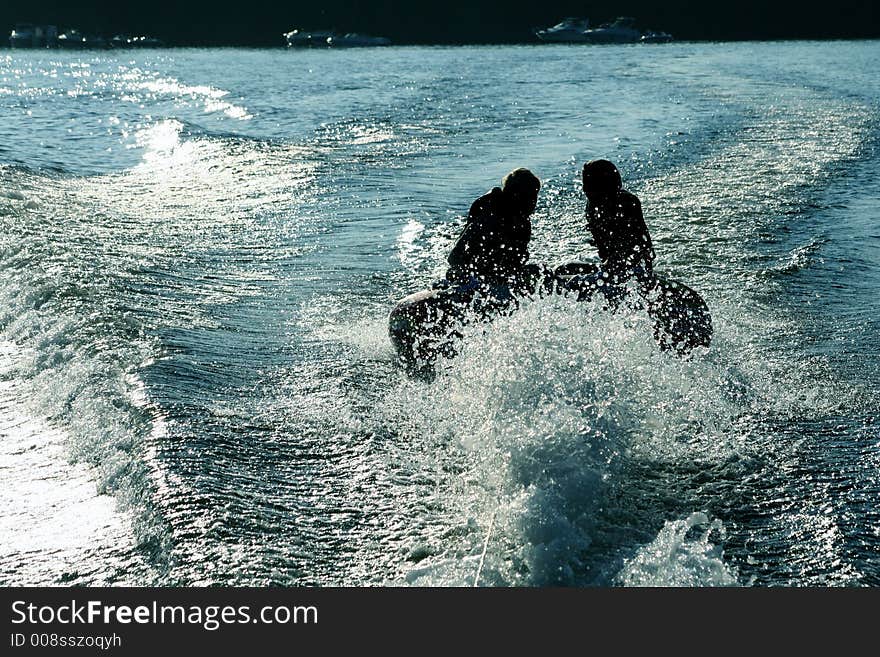 Silhoette of two girls tubing on lake.