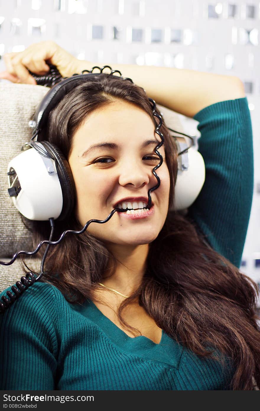 Beautiful young woman listening to music and biting headphone coil. Beautiful young woman listening to music and biting headphone coil