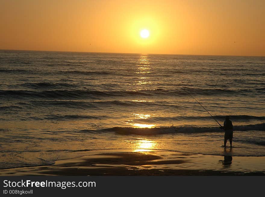 A man is fishing on the Torrey Pines beach in the beautiful San Diego just before sunset. A man is fishing on the Torrey Pines beach in the beautiful San Diego just before sunset.