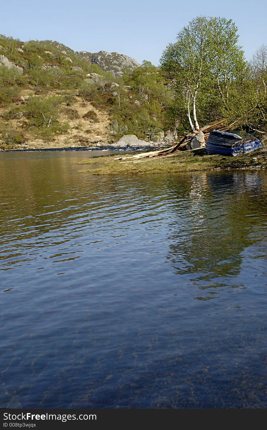 Picture of mountain lake and boat on coast in central Norway.