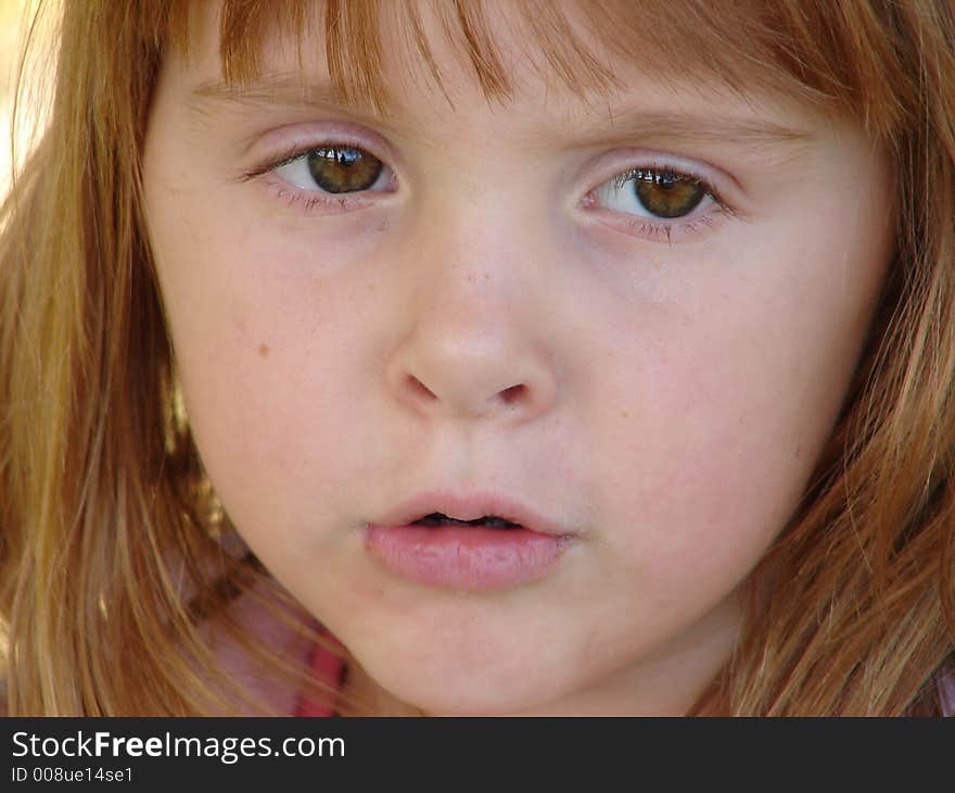 Close up of a little girl with a somewhat serious look on her face.