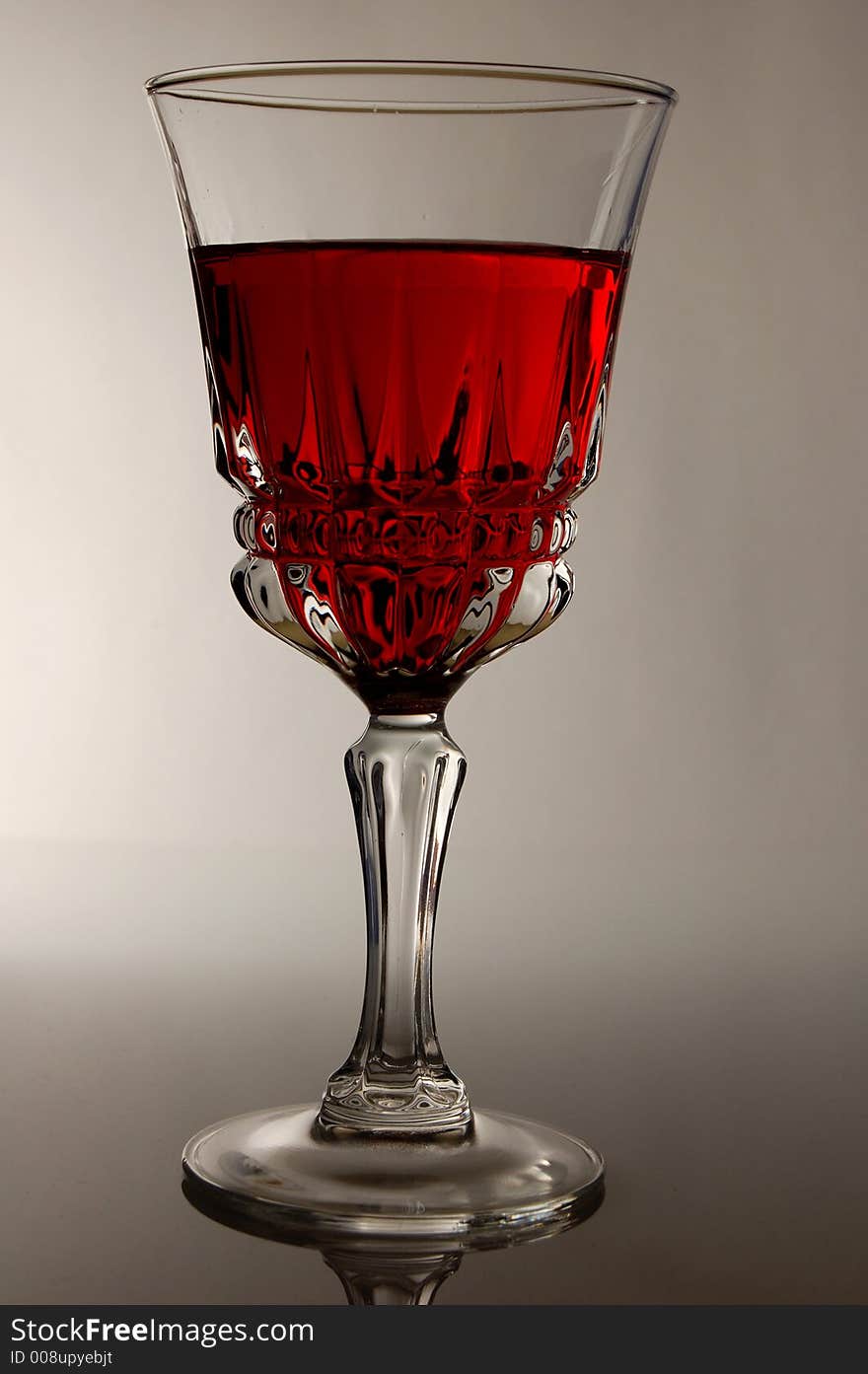 A glass of red wine highlighted from the back