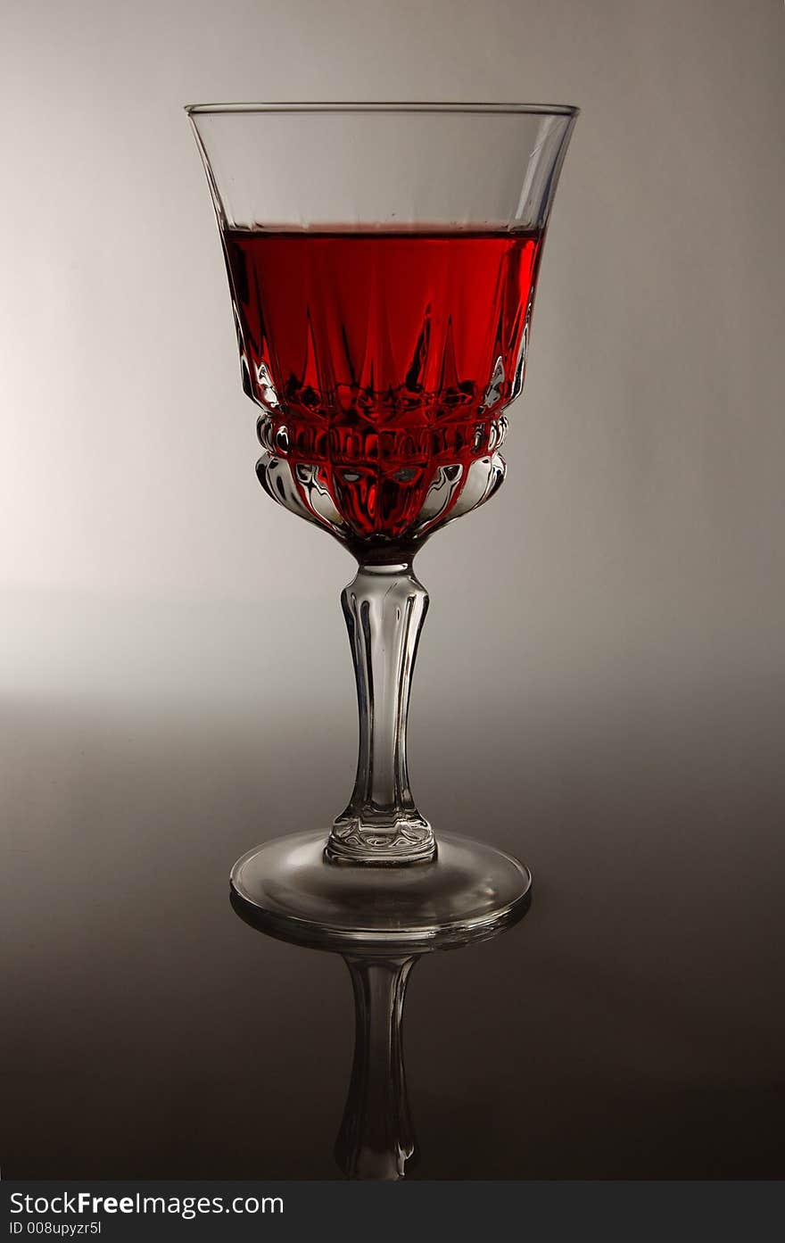 A glass of red wine highlighted from the back