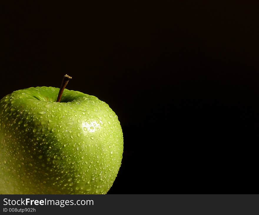 Fresh green apple splashed with water drops