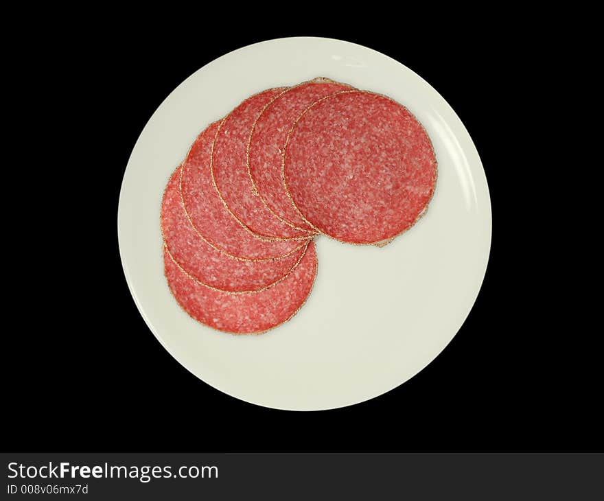 Six slices of salami on a white plate, isolated on black. Six slices of salami on a white plate, isolated on black.